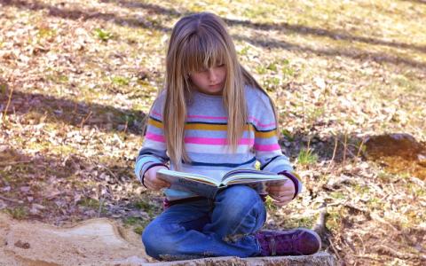 immagine di bambina che legge un libro per evocare il tema della lettura ad alta voce, al centro del bando Ad alta voce 2023, lanciato dal Centro per il libro e la lettura 