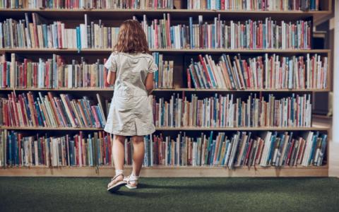 bambina che consulta libri in biblioteca