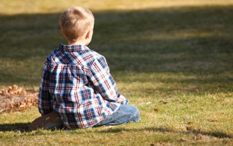 immagine di bambino seduto su un prato per evocare i temi dei diritti dell'infanzia e dell'adolescenza e delle politiche per l'infanzia e l'adolescenza al centro del lavoro della Commissione parlamentare per l’infanzia e l’adolescenza