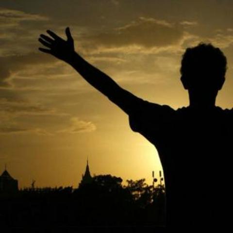 sagoma in nero di un ragazzo con le braccia levate al cielo