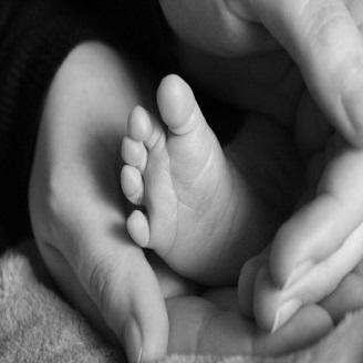 immagine in bianco e nero con mani di adulto che proteggono il piede di un neonato