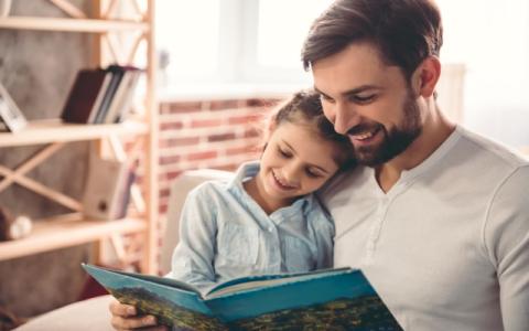 immagine di un padre che legge un libro alla figlia per evocare il tema della lettura condivisa tra padri e figli al centro dell'incontro Papà mi leggi? Buone pratiche per i papà a Milano 