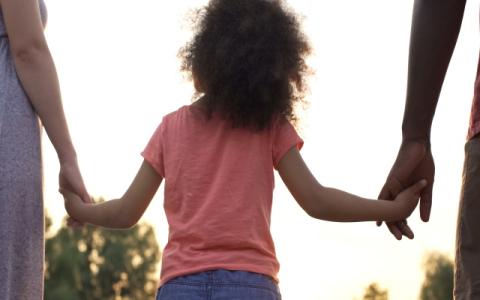 due adulti prendono per mano una bambina