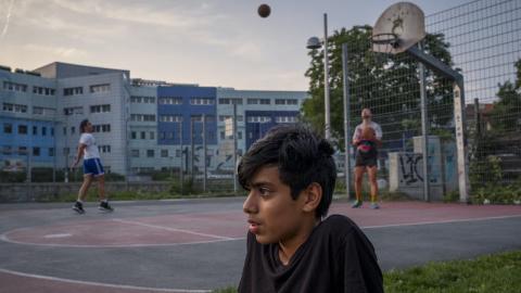 immagine con due persone che giocano a pallacanestro sullo sfondo e in primo piano un ragazzo isolato dal contesto