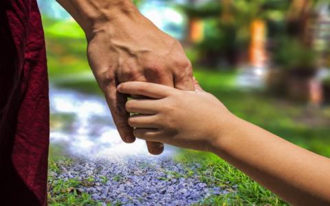 adulto che prende per mano un bambino per evocare il tema della tutela volontaria dei minorenni stranieri non accompagnati al centro del Quinto Rapporto di monitoraggio sul sistema della tutela volontaria dell’Autorità garante per l’infanzia e l’adolescenza