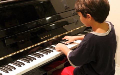 immagine di un bambino che suona il pianoforte per evocare il tema della rassegna La musica unisce la scuola