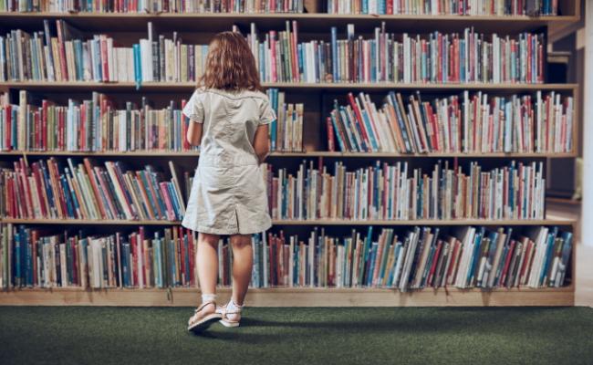 bambina che consulta libri in biblioteca