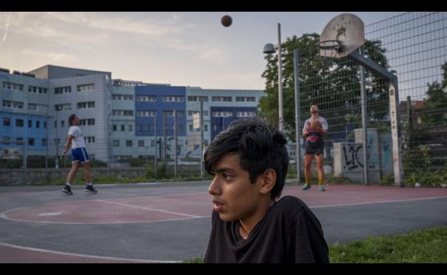 immagine con due persone che giocano a pallacanestro sullo sfondo e in primo piano un ragazzo isolato dal contesto