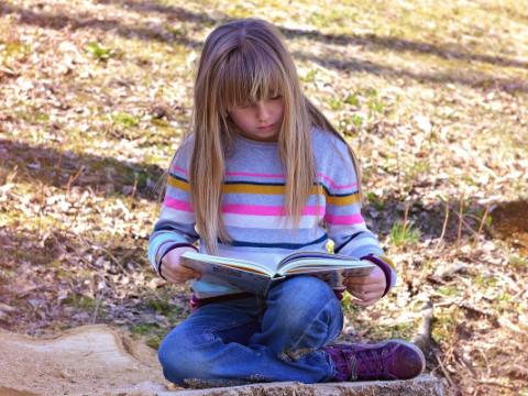 immagine di bambina che legge un libro per evocare il tema della lettura ad alta voce, al centro del bando Ad alta voce 2023, lanciato dal Centro per il libro e la lettura 