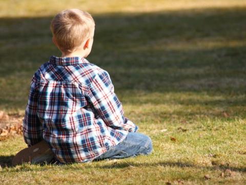 immagine di bambino seduto su un prato per evocare i temi dei diritti dell'infanzia e dell'adolescenza e delle politiche per l'infanzia e l'adolescenza al centro del lavoro della Commissione parlamentare per l’infanzia e l’adolescenza