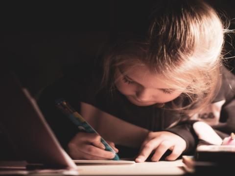 immagine di bambina che scrive per evocare il tema del concorso Cercatori di poesia nascosta
