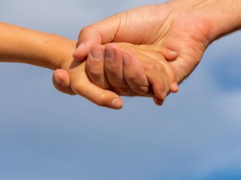 adulto che prende per mano un bambino per evocare il tema dell'affidamento familiare al centro del convegno Parliamo di affido. Le risorse delle famiglie, i bisogni di bambin@ e ragazz@