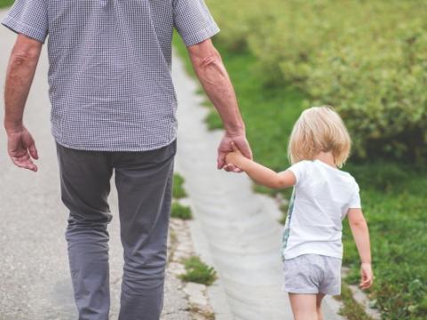 adulto che tiene per mano una bambina per evocare il tema dell'affidamento familiare al centro del convegno L’affido familiare allo specchio. Quali sfide per quale futuro?