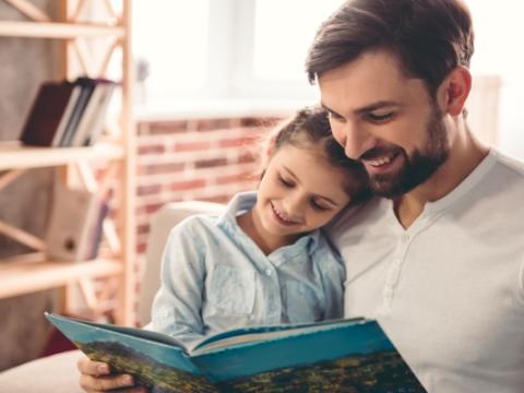 immagine di un padre che legge un libro alla figlia per evocare il tema della lettura condivisa tra padri e figli al centro dell'incontro Papà mi leggi? Buone pratiche per i papà a Milano 