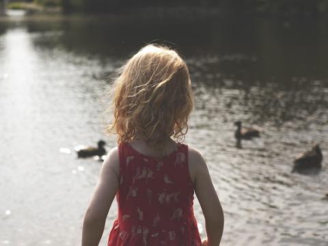 bambina di spalle che osserva un lago