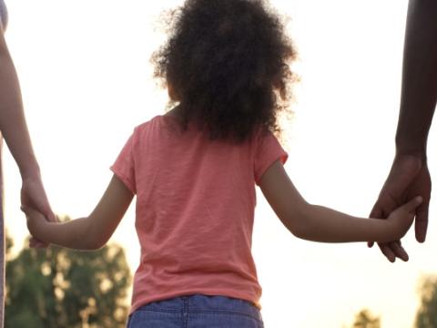 due adulti prendono per mano una bambina