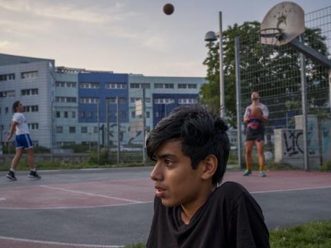 immagine con due persone che giocano a pallacanestro sullo sfondo e in primo piano un ragazzo isolato dal contesto