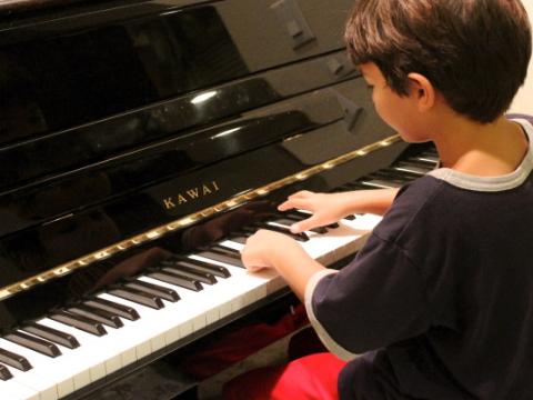 immagine di un bambino che suona il pianoforte per evocare il tema della rassegna La musica unisce la scuola