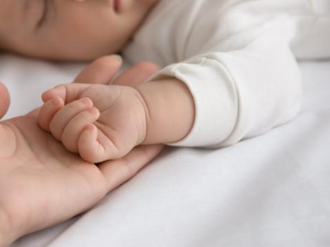 genitore che tocca la mano del figlio neonato